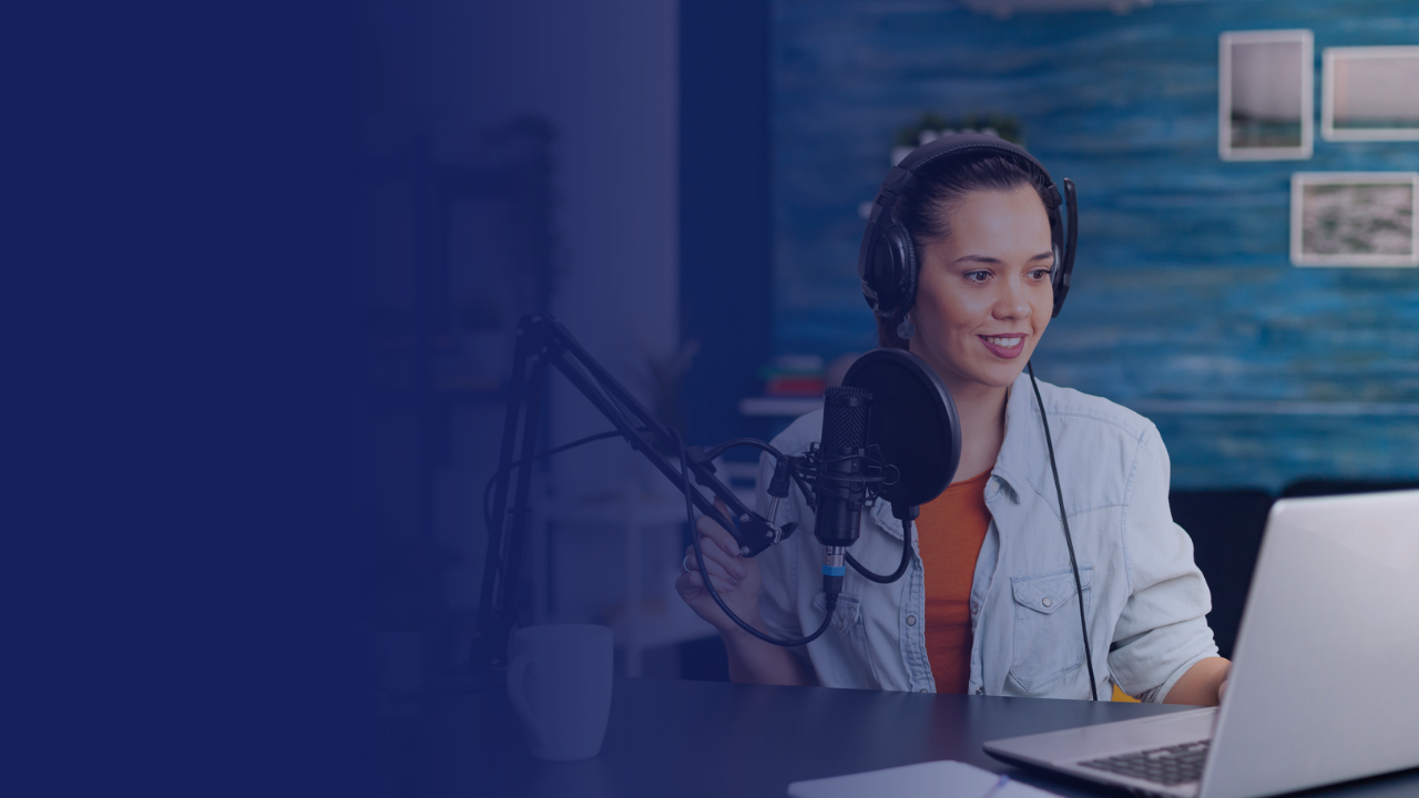 A woman at a desk speaking into a microphone during a podcast recording